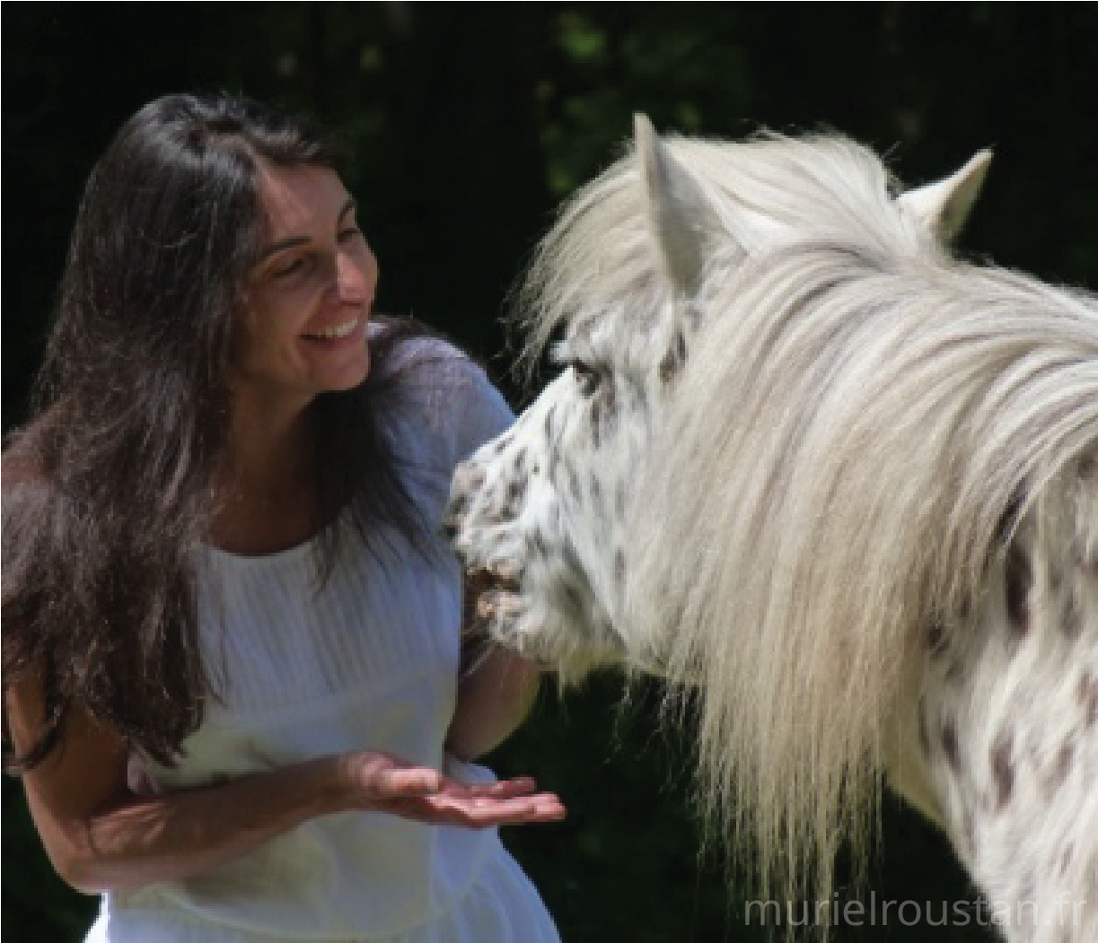 Muriel donnant la main à un cheval tendant son museau vers elle.